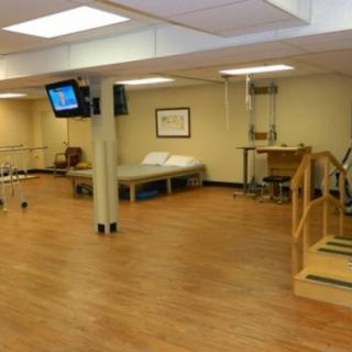 A well-equipped physical therapy clinic featuring exercise equipment and a treatment bed.
