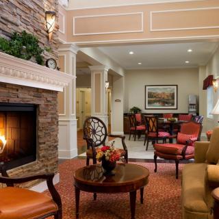 A cozy living room featuring a stone fireplace, elegant furniture, and warm decor.