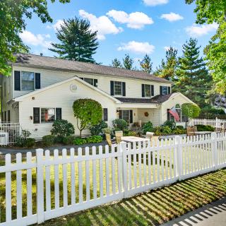 A charming suburban house with a white picket fence and lush greenery.