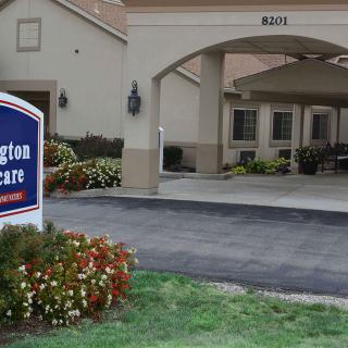 Entrance to a senior living facility with visible signage and landscaped surroundings.