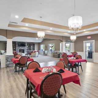 A spacious and elegantly designed dining area with red tablecloths and chandeliers.