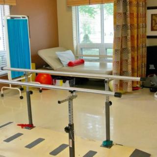 A physical therapy room featuring parallel bars and rehabilitation equipment.