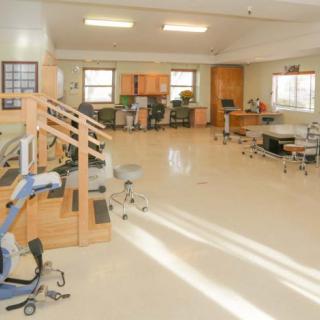 A bright physical therapy room equipped with various exercise machines and rehabilitation tools.