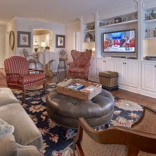 A cozy living room featuring comfortable seating, a patterned rug, a wall-mounted television, and built-in shelving.