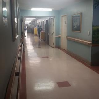 A view of a hospital hallway with patient rooms and clean floors.