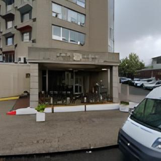 An urban cafe with outdoor seating located on the ground floor of a multi-story building.