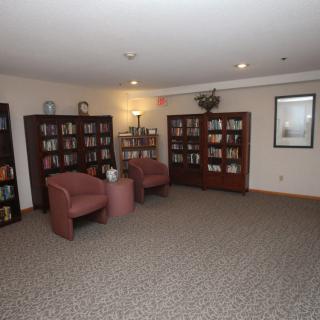A cozy library room with bookshelves and comfortable chairs.