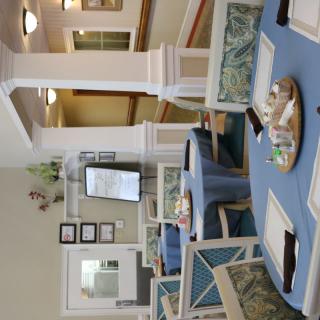 A cozy dining area with neatly arranged tables and chairs, featuring elegant decor and pillars.