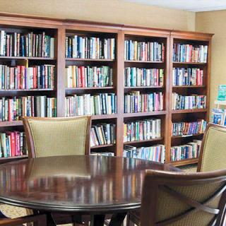 A cozy reading area with bookshelves and a round table surrounded by chairs.