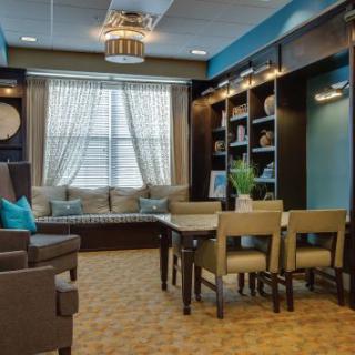 A cozy and modern living room with a window seat, bookshelves, and elegant decor.