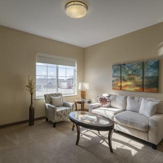 A cozy living room with a sofa, armchair, coffee table, and large window.