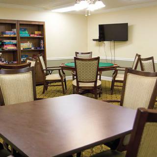 A cozy meeting room with a table, chairs, a wall-mounted TV, and a bookshelf.