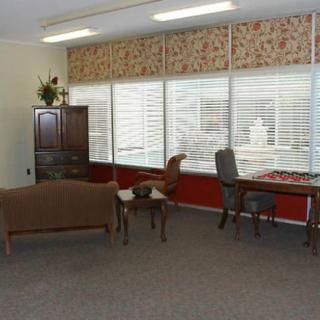 A well-lit office space with large windows, featuring a sofa, desk, chairs, and cabinet.