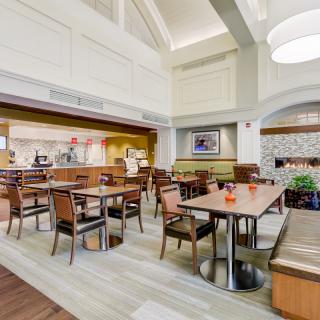 A cozy and modern dining area with neatly arranged tables and chairs, featuring ambient lighting.