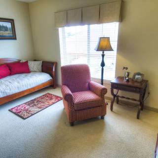 Cozy living room with an armchair, daybed, and lamp by the window.