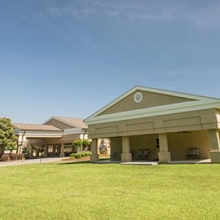 A well-maintained building surrounded by green grass under a clear blue sky.
