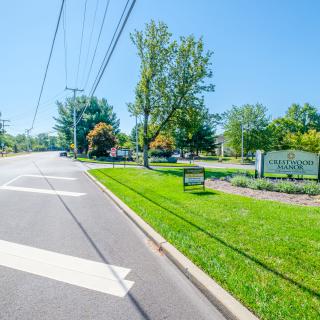 A scenic view of a road with green grass and trees lining the pathway, accompanied by a sign.