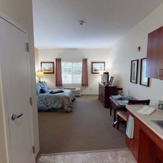 A cozy bedroom with neatly arranged furniture and natural light streaming through the window.