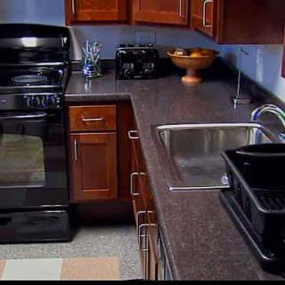 A modern kitchen featuring dark wooden cabinets, a sleek countertop, and essential appliances.