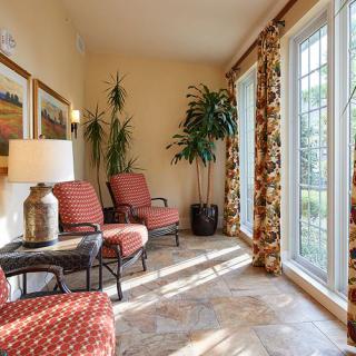 A sunlit room with comfortable seating, large windows, and vibrant plants.