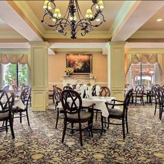 An elegant dining room interior with neatly arranged tables and chairs, adorned with a chandelier.