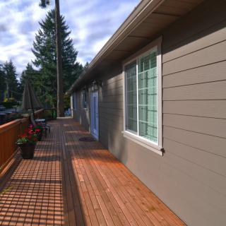 A wooden deck extending along the side of a house on a sunny day.