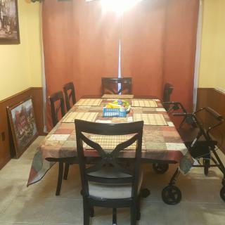 A dining room with a table and chairs, featuring a colorful tablecloth and a walker nearby.