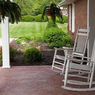 A peaceful porch with white rocking chairs and lush greenery.