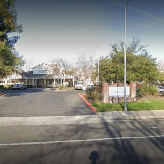 A suburban building with a parking lot and trees along the road.