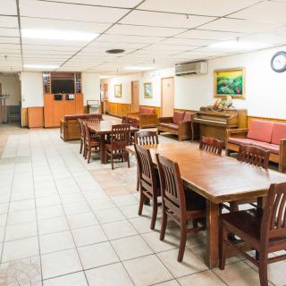 An empty restaurant interior with wooden tables and chairs, featuring tile flooring.