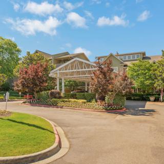 A scenic view of a building with a covered entrance, surrounded by trees and a clear blue sky.