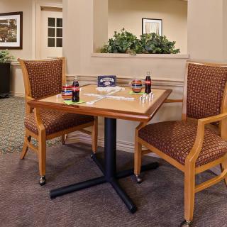 A dining table set with two chairs in a cozy indoor setting, featuring two Coca-Cola bottles.