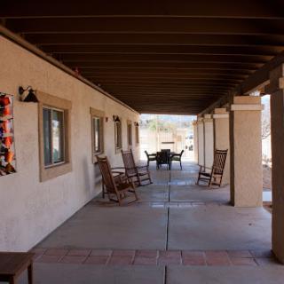 A serene outdoor porch area featuring wooden rockers, perfect for relaxation in a desert setting.