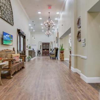 A spacious and elegantly designed hallway with a chandelier and wooden flooring.