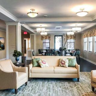 A well-furnished living room with a cozy sofa and armchairs, featuring stylish lighting and decor.