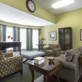 A cozy living room with modern furniture and a large clock on the wall.