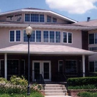 A two-story residential building with a landscaped entrance and multiple windows.