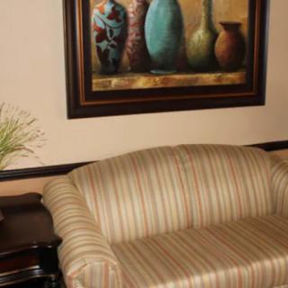 A cozy living room with a striped sofa and a painting of vases on the wall.