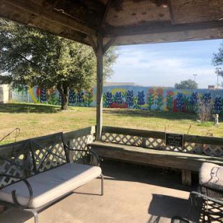 A peaceful gazebo view overlooking a colorful fence and lush greenery.