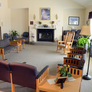 A cozy waiting room featuring comfortable seating, a fireplace, and decorative plants.