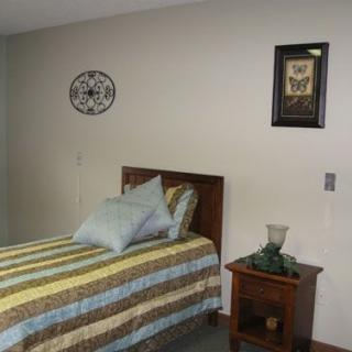 A simple and cozy bedroom with a single bed, nightstand, and decorative wall art.