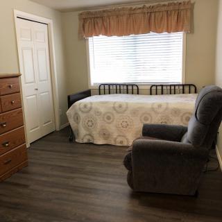 A cozy bedroom with a single bed and an armchair next to the window.