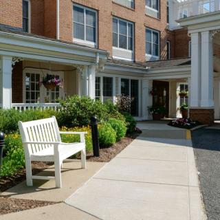 The entrance to a building featuring a white bench and well-maintained landscaping.