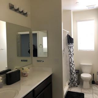 A modern bathroom featuring a clean design with mirrors, a shower area, and natural lighting from the window.