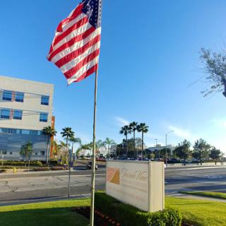 A clear day featuring the American flag in front of a modern building.
