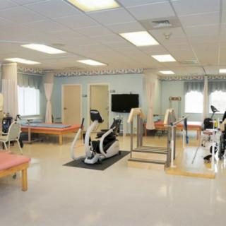 A spacious rehabilitation and physical therapy room equipped with exercise machines and tables.