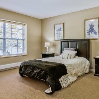 A cozy bedroom with a neatly made bed and minimalist decor.