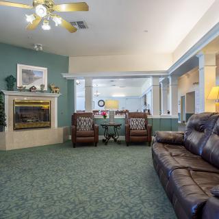 A cozy living room with a fireplace, comfortable seating, and a ceiling fan.
