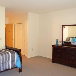 A tidy bedroom featuring a bed, dresser with a mirror, and closet space.