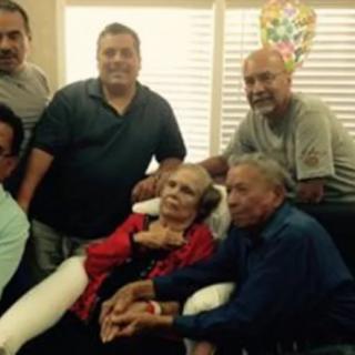 A group of people gathered around an elderly person indoors.